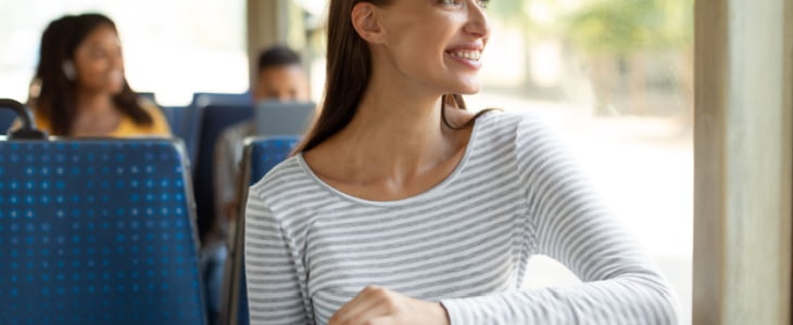 woman smiles while looking out of a bus window